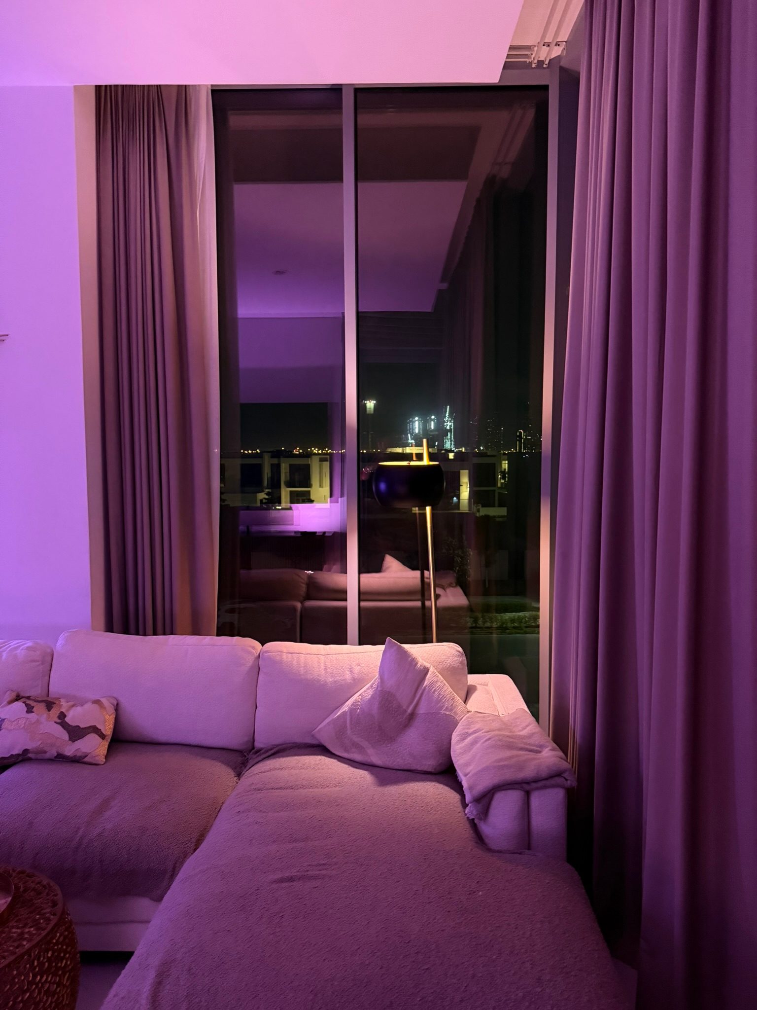 Dubai apartment living room with purple ambient lighting and night city view